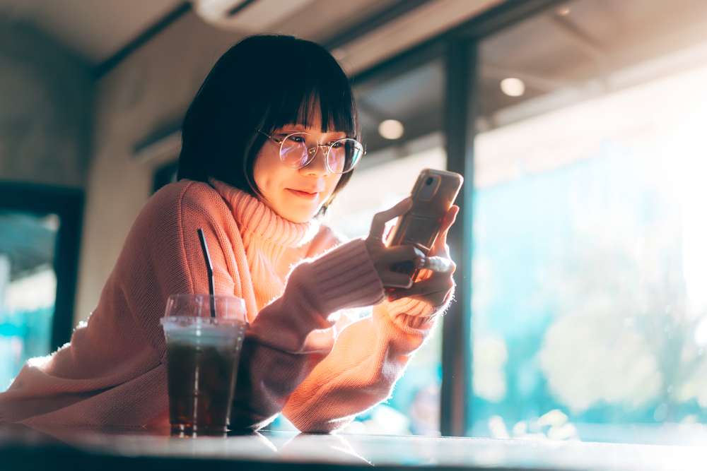 Young Adult Woman using a Mobile Phone at a Cafe