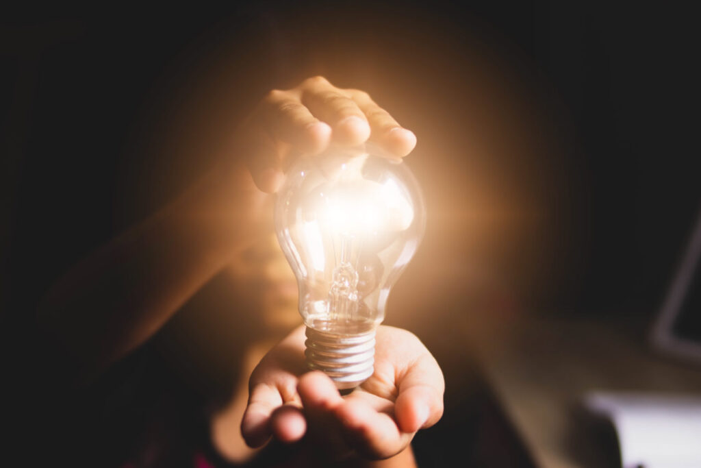 A person holding a glowing bulb